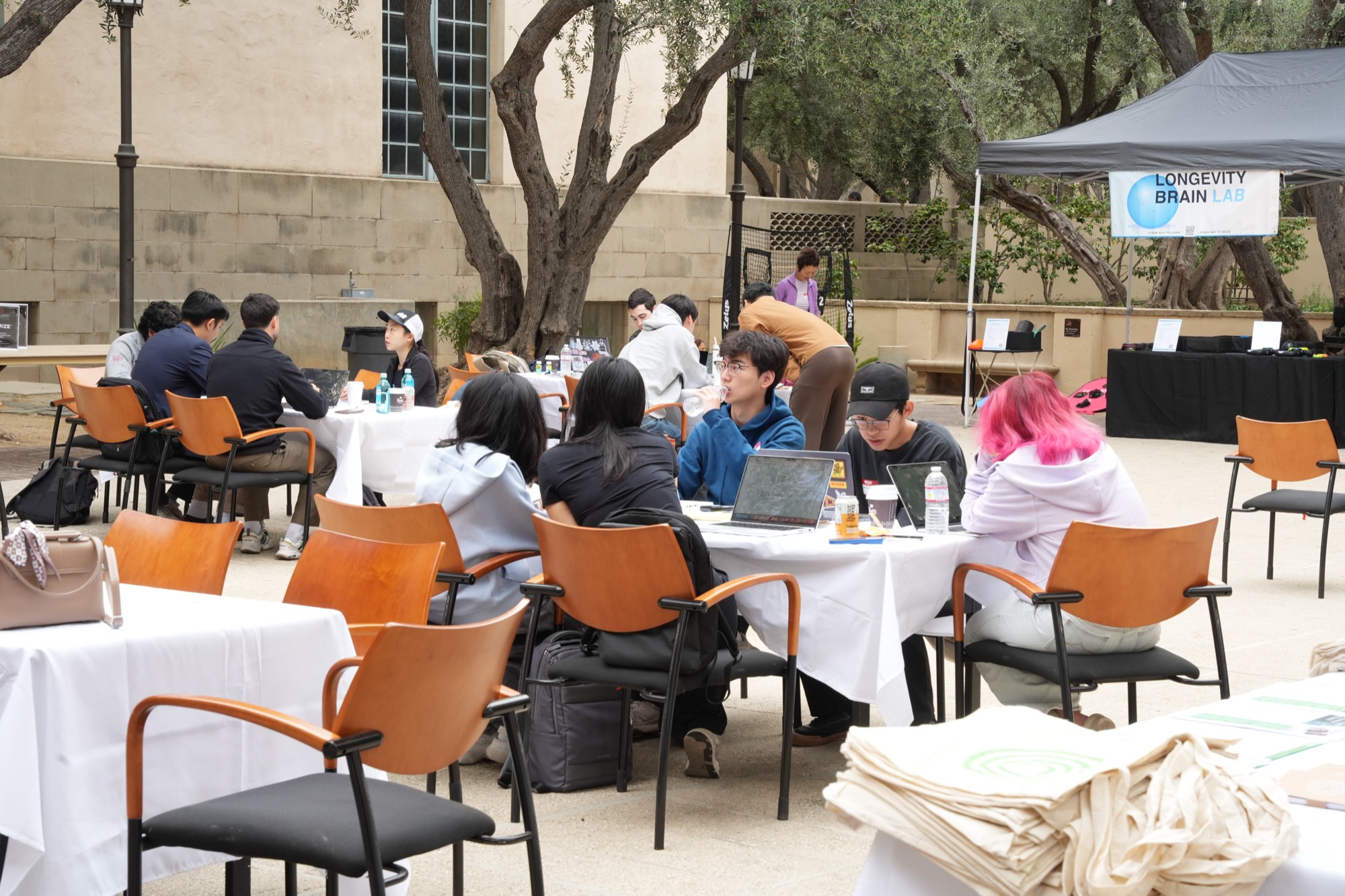Teams collaborating at courtyard tables next to the Brain Lab tent